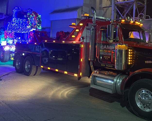 Heavy-duty Camp Auto wrecker recovering a tractor trailer at night
